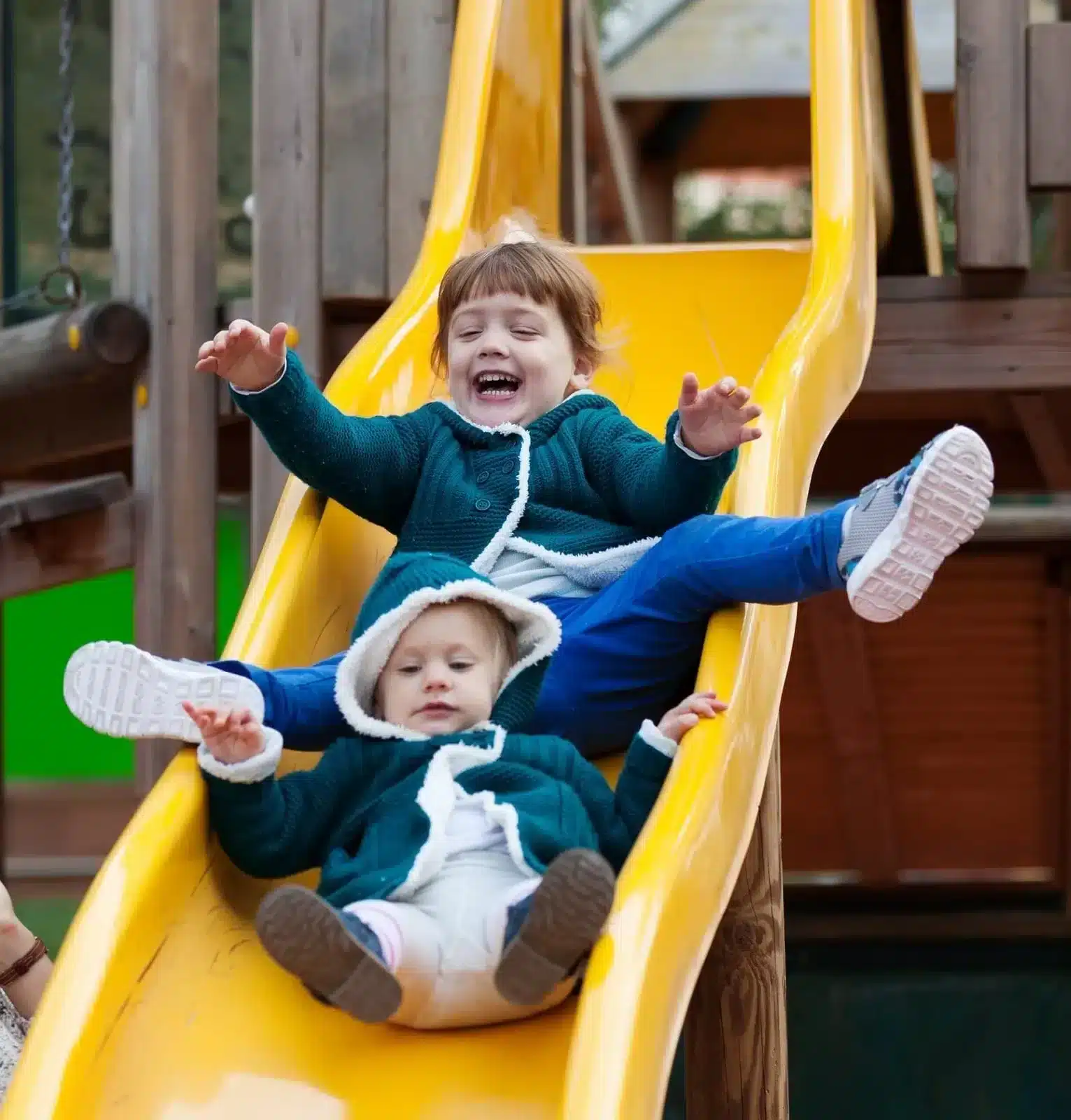 Two Kids playing Slider and sliding down