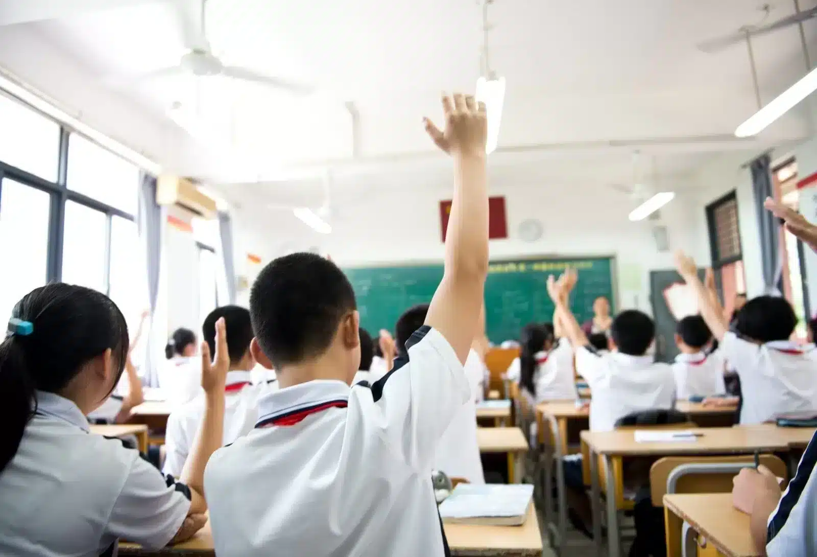 Children raising hands in class