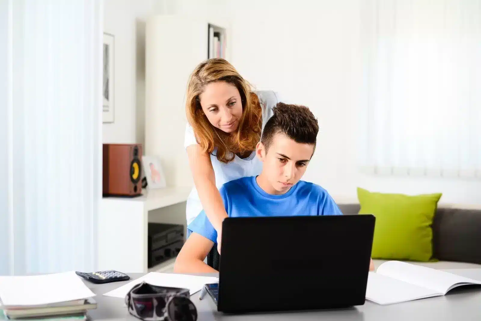 Boy Study with laptop with his mother in his back teaching