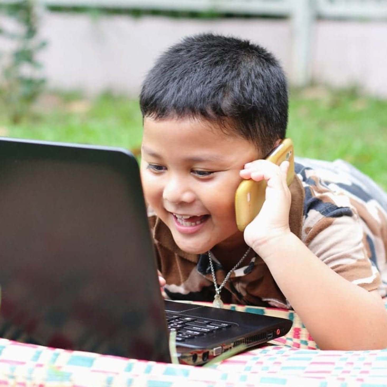 Boy Playing Laptop with his hands on phone calling