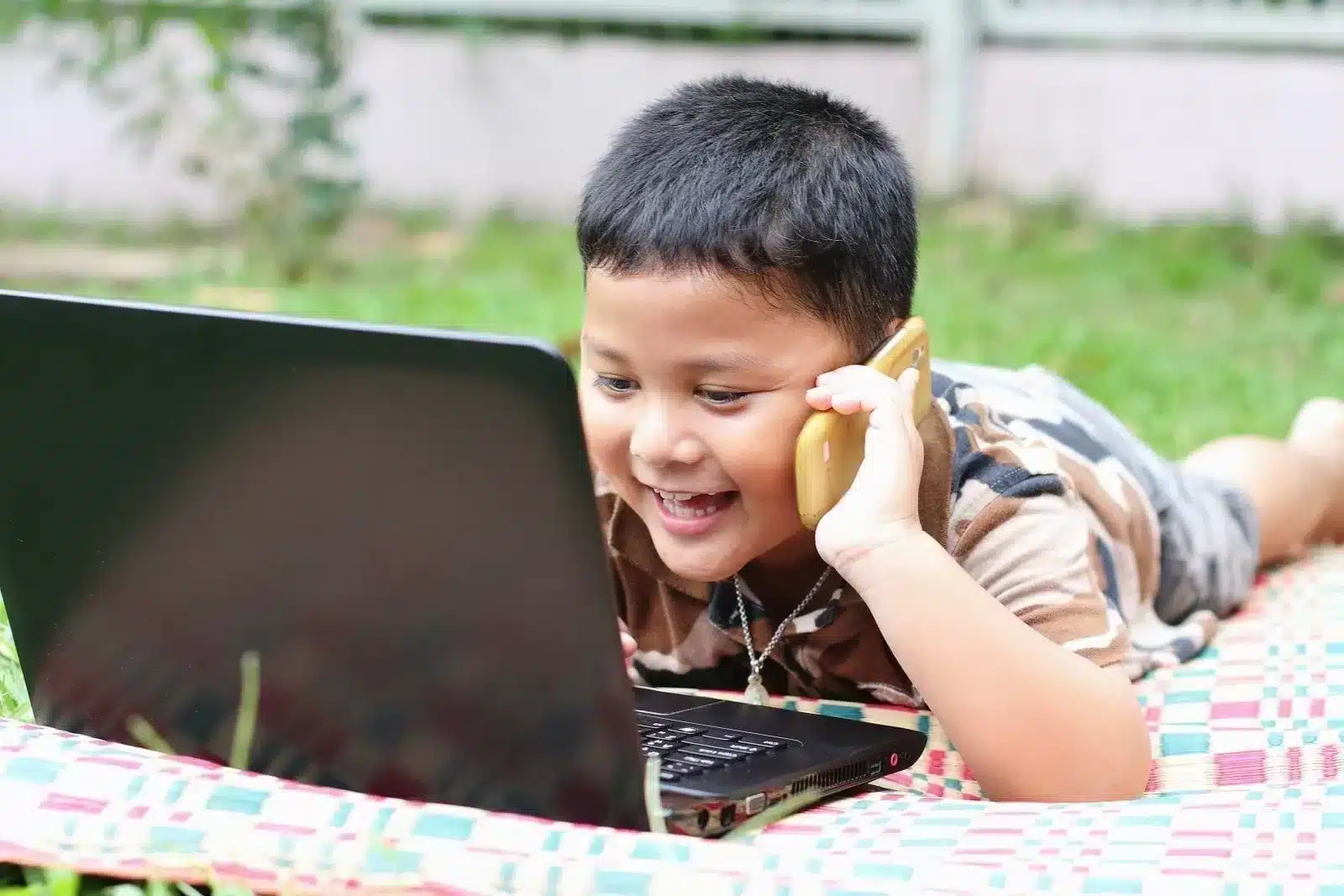 Happy boy playing with laptop and call someone