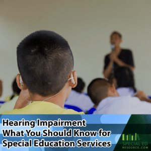 Boy with a hearing impairment sitting in a classroom at school using hearing aids.